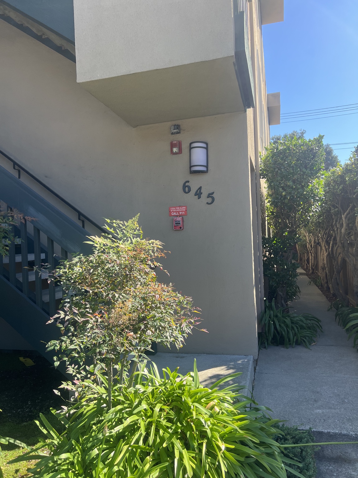 Front entrance of 645 Rollins Road with the building number 645, stairs, and side walkway